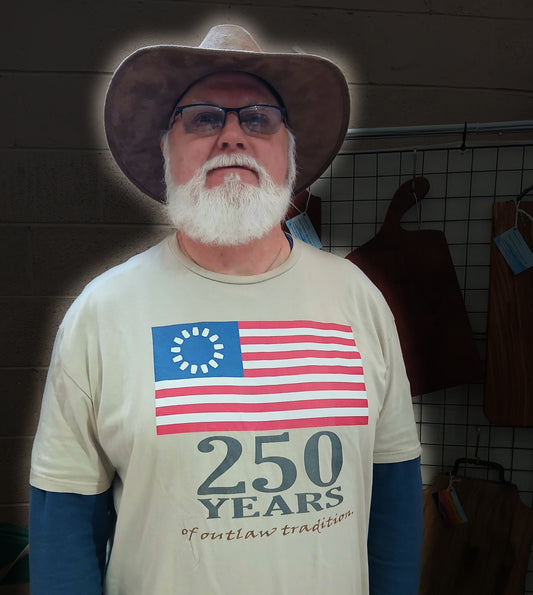 Reclusive blues guitarist Port Tampa Blue wearing the 250 Years of Outlaw Tradition shirt at an undisclosed location.